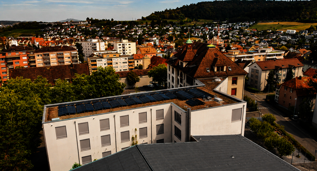 Photovoltaikanlage auf dem begrünten Flachdach des Schulhauses Kirchacker in Neuhausen am Rheinfall mit Blick über die Gemeinde.
