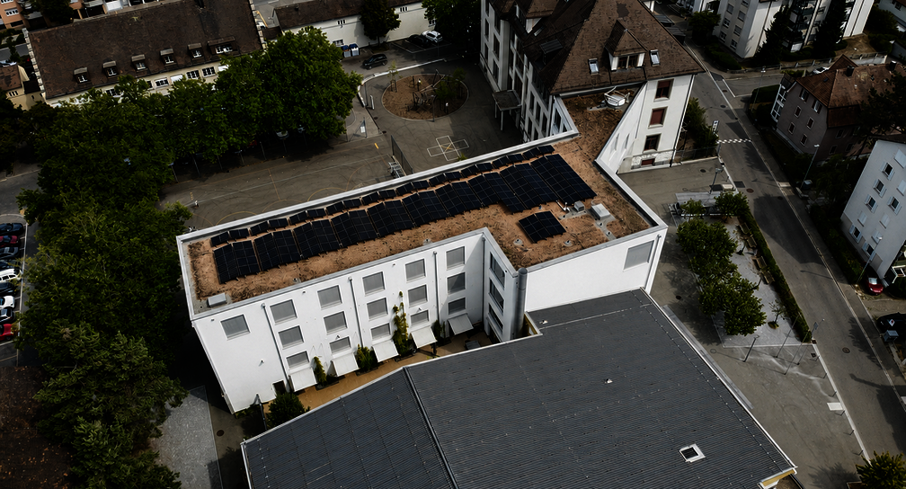 Photovoltaikanlage auf dem Schulhaus Kirchacker in Neuhausen am Rheinfall aus der Vogelperspektive mit Schulgebäuden und Umgebung.